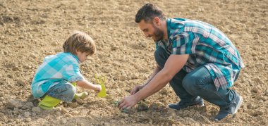 Spring farming. Dad and child boy farmers planting sprouts on farm, spring banner. Father and son planting in soil, earth ground