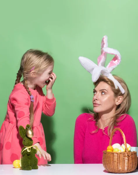 Ester for mother and daughter. Mom with little cute girl are preparing for Easter. Mother and daughter wearing bunny ears are kissing. Easter banner, mockup copy space, poster flyer header