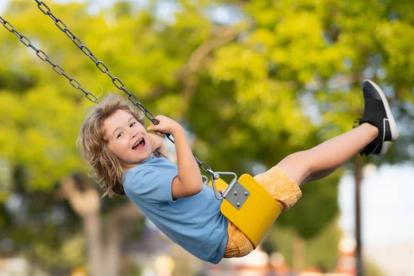 Outdoor playground. Funny kid on swing. Little boy swinging on playground. Happy cute excited child on swing. Cute child swinging on a swing. Crazy playful child swinging very high