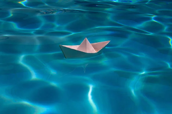 Paper boat sailing on water causing waves and ripples. Paper boat into water. Concept of tourism, travel dreams vacation holiday, dreaming traveling, sailing adventure. Paper art style