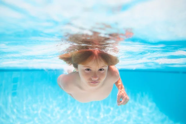 Summer kids in water in pool underwater. Underwater boy in the swimming pool. Cute kid boy swimming in pool under water