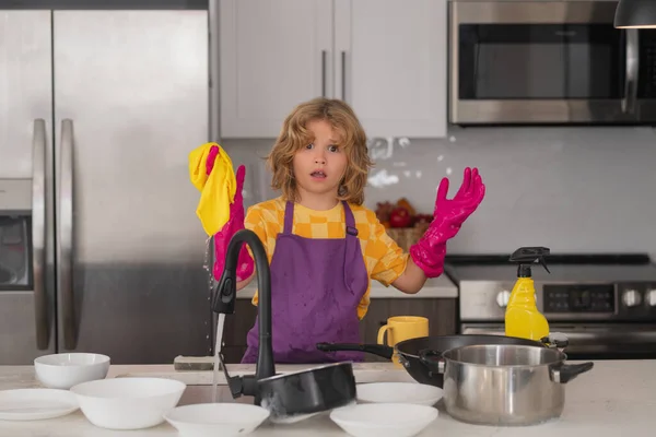 Cleaning at home. Child helping with household, wiping dishes in kitchen. Child helper housekeeping. Little boy sweeping and cleaning dishes at kitchen