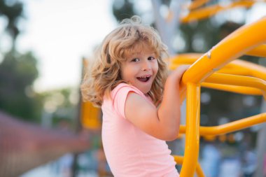 Funny child boy plays on playground. Kid climbing on playground