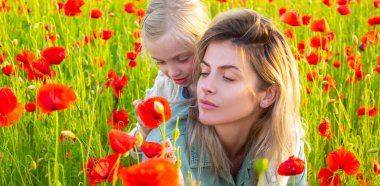Mother and daughter on the poppies field background. Spring family banner. Woman with child girl in field with red poppies. Mother and daughter are playing in the field of flowering red poppies