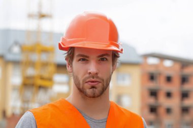 Construction worker man in work clothes and a construction helmet. Improvement and renovation. Brutal man builder. Engineer builder in uniform. Young businessman construction site engineer