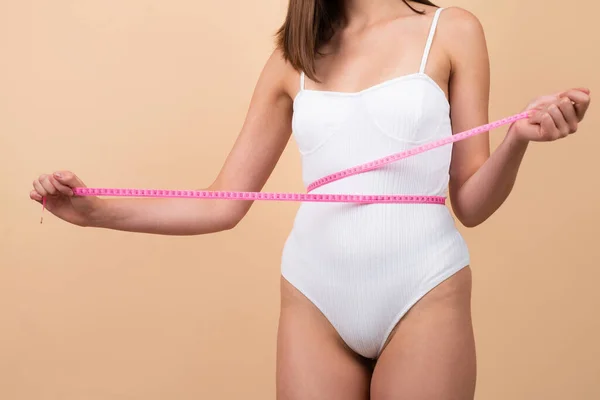 Perfect slim body. Fit woman measuring her waist isolated background