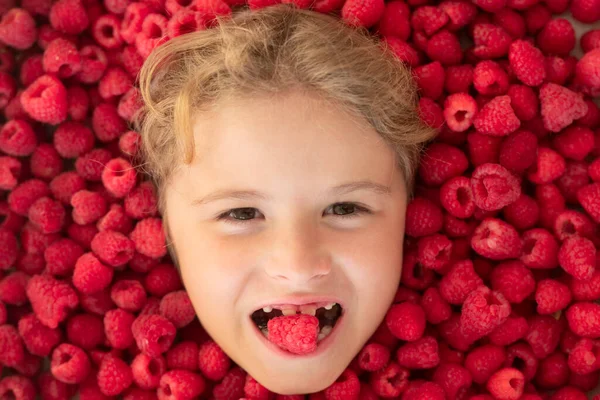 Raspberry in kids mouth. Kids face in raspberries fruits, healthy kids nutrition concept