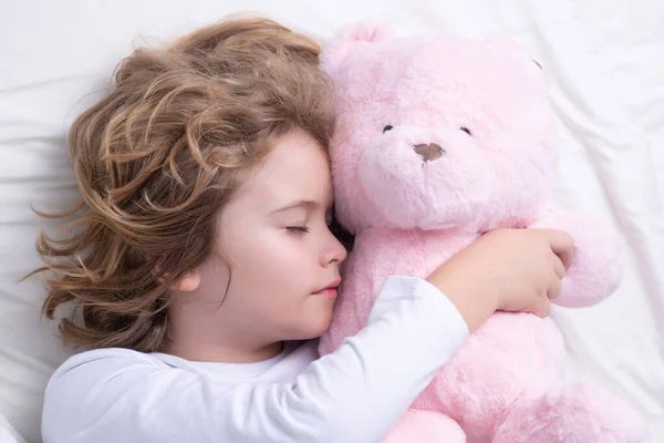 Daily sleep. Child sleeping with a toy teddy bear on bed. Bedtime, kids sleeps. Kid asleep on pillow, having healthy sleep