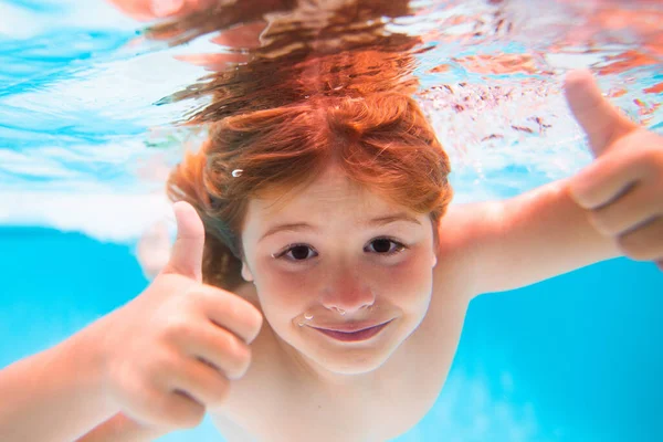 Child face underwater with thumbs up. Funny kids face underwater. Underwater boy in the swimming pool. Cute kid boy swimming in pool under water. Summer kids in sea water on beach