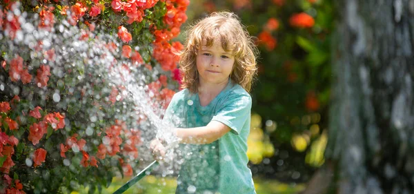 Spring child watering, banner. Child watering flowers and plants in garden. Kid with water hose in backyard. Kids gardening. Kids summer fun outdoor at home
