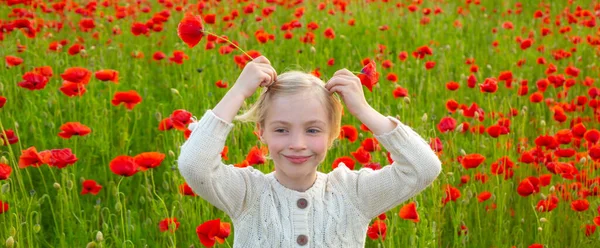 Spring and kid. Wide photo banner for website header. Portrait of beautiful child girl are wearing casual clothes in field of poppy flowers. Family on spring poppy field