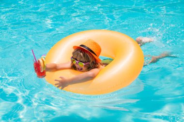Boy kid in pool drinking cocktail. Happy lifestyle kids. Water toy, healthy outdoor activity for children. Kids beach fun. Child in swimming pool with inflatable toy ring