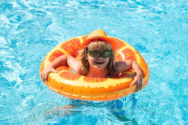Child swimming in pool play with floating ring. Smiling cute kid in sunglasses swim with inflatable rings in pool in summer day
