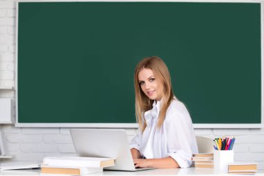 Sınıfta dizüstü bilgisayarla çalışan bir üniversite öğrencisi sınava hazırlanıyor. Üniversite sınıfında başarılı bir bayan öğrenci.