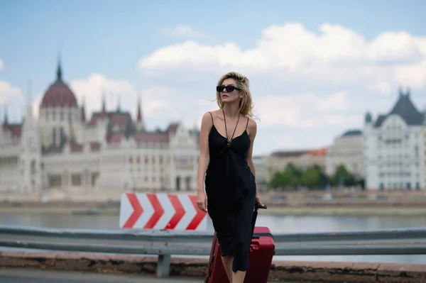 Europe trip. Tourist sexy woman in Budapest. Traveler tourist girl in trendy dress with suitcase. Female model travel abroad weekends. Journey concept