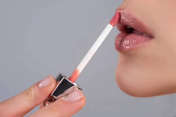 Close up painting lips with bright lipstick. Female lipstick. Close-up perfect natural lip