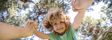 Babaların eli. Ağacın dalından oğluna yardım eden bir baba. Bahar bayrağı