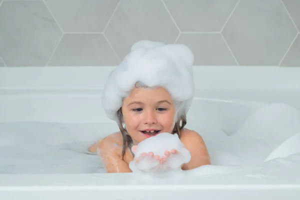 Bath tub with soap bubble. Child playing with foam in bathtub. Little boy takes a bath with a large amount of foam