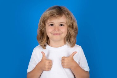 Child showing thumbs up on studio isolated background. Portrait of kid boy making thumbs up sign