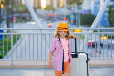 Portrait of child traveler with travel bag. Little tourist with suitcase ready to travelling