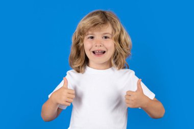 Excited kid boy with thumbs up on studio isolated background. Surprised face, amazed emotions of child