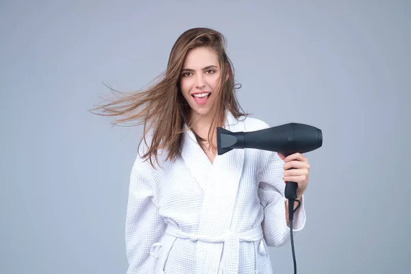 Woman with hair dryer in a studio
