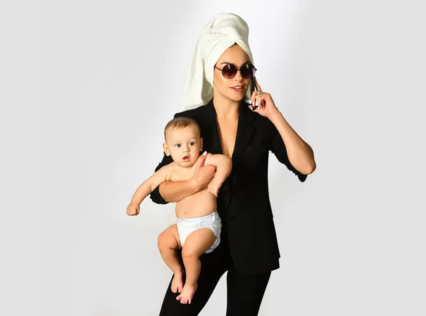 Mother business woman and her baby child in studio. Loving mom working with her child. Portrait of busy mum mother hugging her child. Mothers day for businesswoman