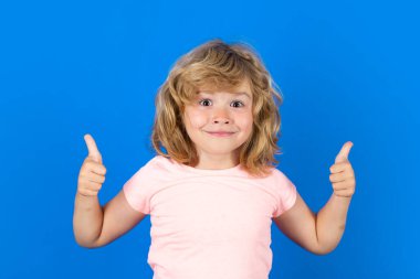 Child showing thumbs up on studio isolated background. Portrait of kid boy making thumbs up sign