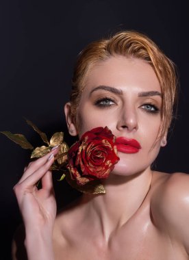 Beauty studio portrait. Beautiful model with red rose flower, isolated on black studio background. Charming young girl with perfect makeup