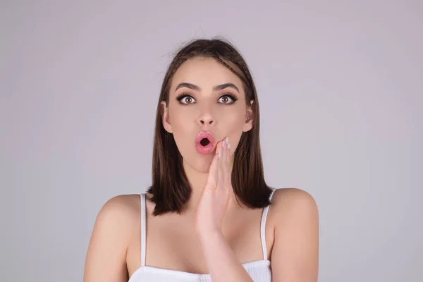 Excited fun young woman with surprised open mouth on studio background. Amazed astonished portrait of excited funny girl. People emotions. Wow. Beautiful girl shocked surprised stunned. Human emotion