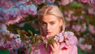 Kirazlı sakura çiçekli kız. Çiçek dallı güzel genç bir kadın, bahar çiçekleri bahçesindeki genç bir kadın. Pankart veya web sitesi başlığı için bahar tasarımı, kopyalama alanı