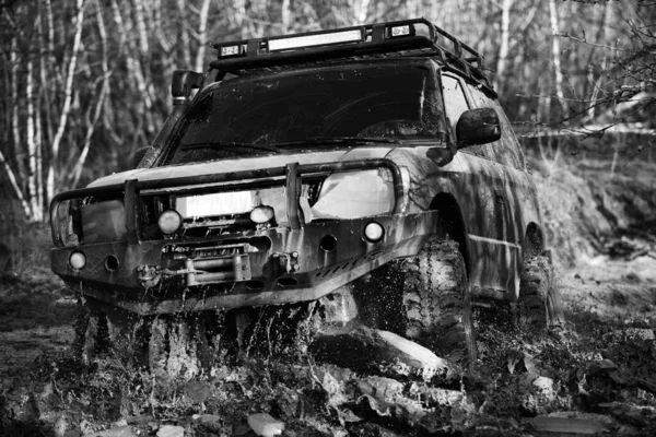 オフ山の風景の間の道路スポーツトラック 泥の上をオフロードカー サファリだ最高のオフロード車 ジープはパドルに押しつぶされ 汚れのスプレーを拾いました — ストック写真