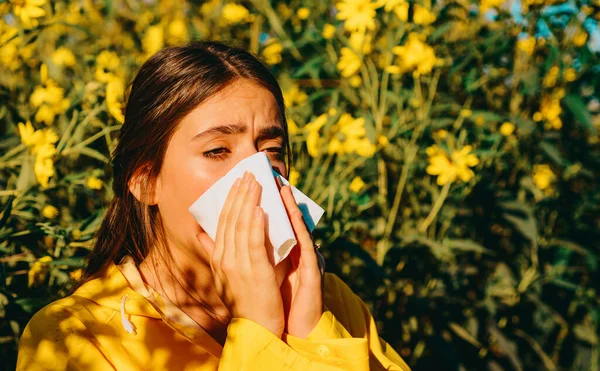Woman with napkin fighting blossom allergie outdoor. Allergy to flowering. Young woman is going to sneeze. Sneezing and runny nose from pollen. Allergy medical seasonal flowers concept