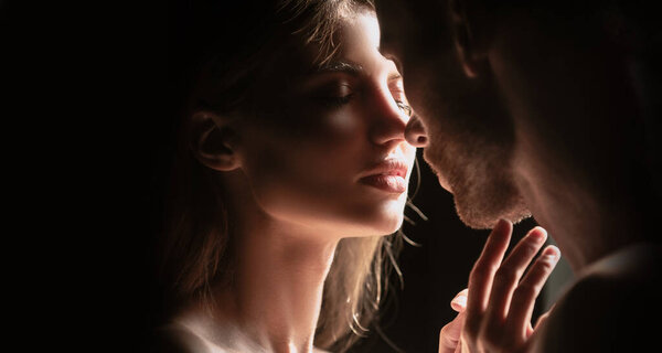 Portrait of lovely couple in love. Young sensual girlfriend glad to passionate kiss from her boyfriend. Handsome man embraces his woman and kisses. Romantic night date