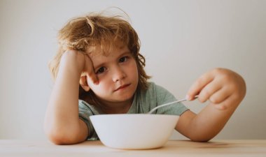 Küçük hoşnutsuz çocuk pirzola ile makarna yemek istemiyor. Küçük çocuk yemek istemiyor..