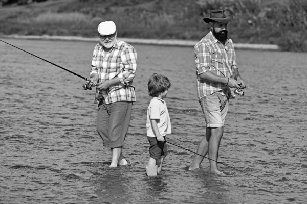 Fly fisherman using fly fishing rod in river. Family generation and people concept. Grandson with father and grandfather fishing by lake