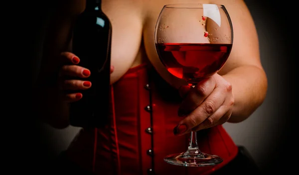 ワインとワインのボトルでガラスを保持し 大きな美しい胸を持つプラスサイズの女性 ビクトリア様式の赤いコルセットを身に着けている大きなおっぱいを持つセクシーな熱い女性 甘いワインと女性のコンセプト — ストック写真