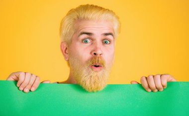 Sarı arka planda boş bir ilan panosu tutan adam.