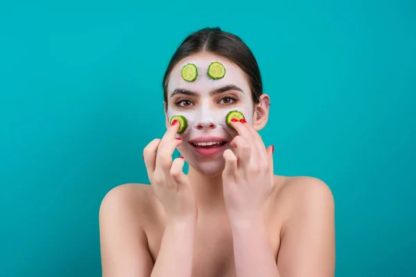 Facial mask of cucumber. Beautiful woman with facial mask with slices of fresh cucumber on face. Cosmetic masks on face. Portrait of beautiful spa girl. Beauty, healthcare