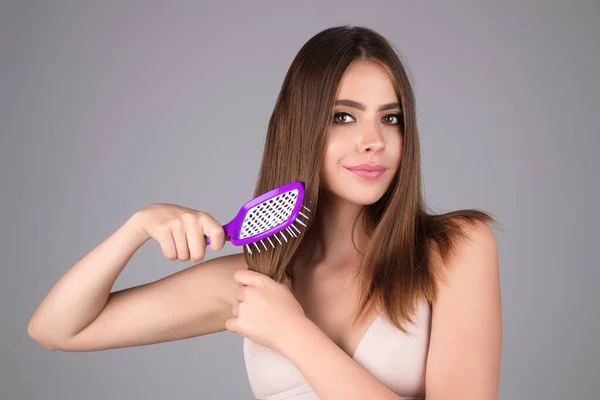 Girl combing hair with comb. Beautiful young woman holding hair comb. Female model hold comb near face. Woman portrait with comb