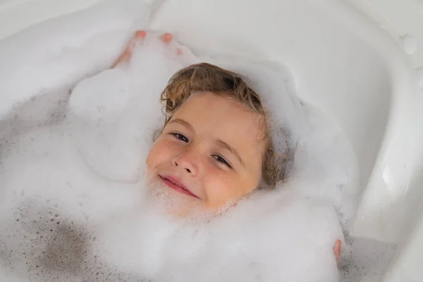 Kids face in foam. Child bathes in a bath with foam