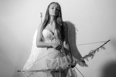 Sihirli anın tadını çıkarıyorum. Aşkın oku. Sevgililer günün kutlu olsun - fotokopi alanı. Sevgililer gününde aşk tanrısı. Beyaz elbiseli ve kanatlı çekici kıvırcık kadın. Melek gibi bir kız.