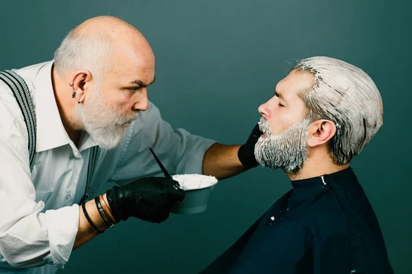 Process of dyeing hair for man at beauty salon, male closeup portrait. Dying hair of man. Bearded man in beauty salon