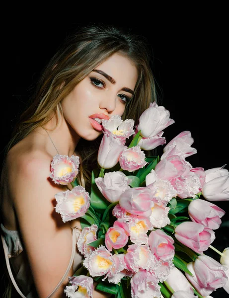 Sexy sensual young woman with tulips flowers bouquet. Spring woman on black
