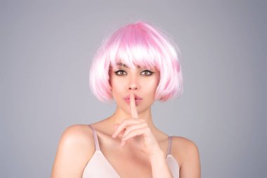 Woman asking for silence and quiet, gesturing with finger in front of mouth, saying shh, keeping a secret. Girl on studio background asking to be quiet with finger on lips. Silence and secret