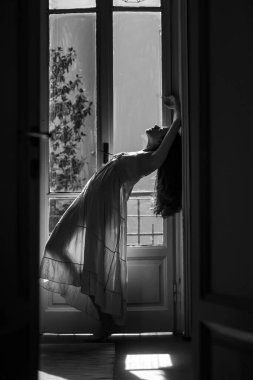 O mutlu dans eder. Balkonun yanında duran genç bir kadın. Yalnız bir kadın. Kendine güveni tam seksi bir kız. Tutku ve cazibe. Kız gece elbisesi giymiş.