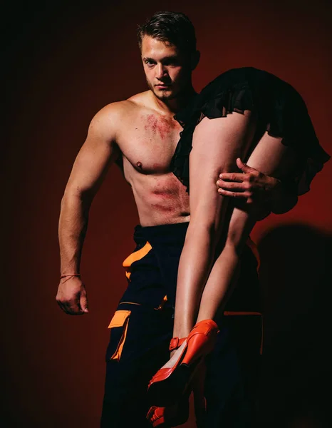 Firefighter sexy body muscle man holding saved sexy woman. Intimate relationship and sexual relations. Hot sexy Firefighter. Superhero. Passion and sensual touch