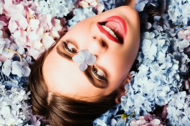 Doğa güzelliği. Çiçeklerin üzerinde yatan kadın. Doğayla birlik. Çiçek. Makyaj malzemeleri ve cilt bakımı. Ortanca çiçekli kız