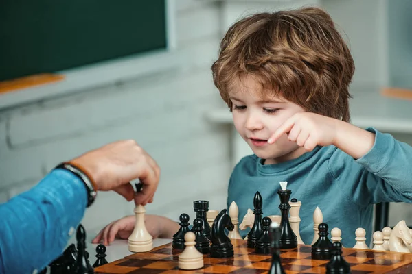 Kids educational games, early development. Boy kid playing chess at home. Games and activities for children. Family concept