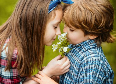Şirin çocuklar karahindiba üflüyor. Çocuklar çayırda oturmuş karahindiba çiçeklerini üflüyorlar mutlu ve neşeli oluyorlar.